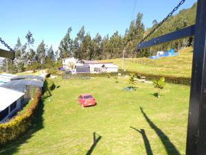 eine Person, die in einem Hof mit einem roten Auto steht in der Unterkunft Hotel Chimeneas del Dorado in Sesquilé