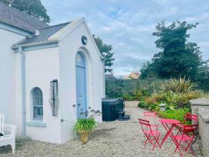 a small white building with red chairs and tables at Preachers Rest in Killough