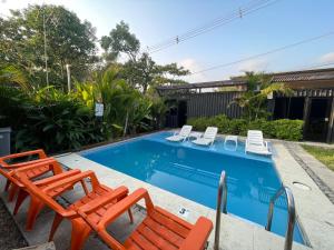 a swimming pool with two lawn chairs and a pair at The Cabins in La Libertad