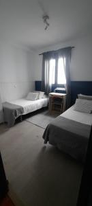 1 dormitorio con 2 camas y ventana en Casa Faro de Arinaga, en Arinaga