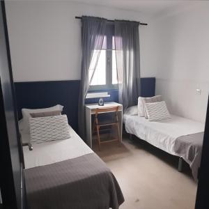 Una habitación con dos camas y una mesa y una ventana. en Casa Faro de Arinaga, en Arinaga