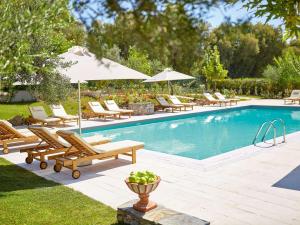 a swimming pool with chairs and umbrellas next to at Grecotel Villa Oliva in Adelianos Kampos