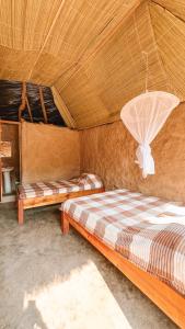 two beds in a room with a roof at Muke Village Guest House in Livingstone