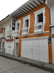 Hotel Casa Blanca في Aguadas: مبنى برتقالي وبيض مع كراج ابيض