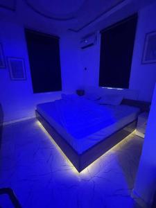 Modern 1bedroom Duplex في بورت هاركورت: غرفة بها سرير مع أضواء زرقاء