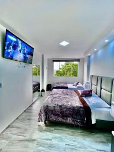 Hotel Casa Blanca في Aguadas: غرفة نوم مع سرير وتلفزيون على الحائط