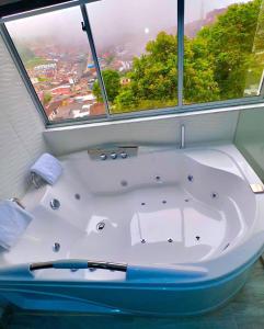 Hotel Casa Blanca في Aguadas: حوض استحمام في حمام مع نافذة كبيرة