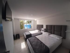 een hotelkamer met 2 bedden en een raam bij Hotel Casa Blanca in Aguadas