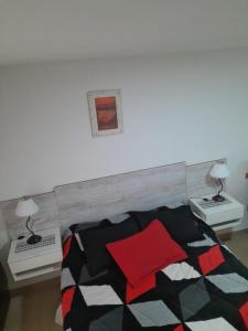 1 dormitorio con 1 cama con almohada roja y 2 mesas en monoambiente Albarracín en San Carlos de Bariloche