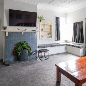 a living room with a fireplace with a tv and a table at Sahara Deluxe Studios in Dunedin