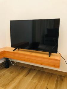 TV de pantalla plana grande con soporte de madera en AMU- Apartamentos Mistérios da Urzelina, en Urzelina