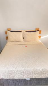Una cama con sábanas blancas y almohadas. en Espaço Zoey en Búzios