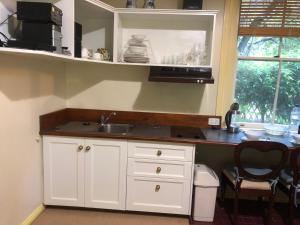 a kitchen with white cabinets and a sink and a window at Secrets Hideaway in Blackheath
