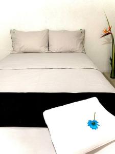 Una cama con dos almohadas y una flor azul. en Apartaestudio Zona Norte - Vipasa en Cali
