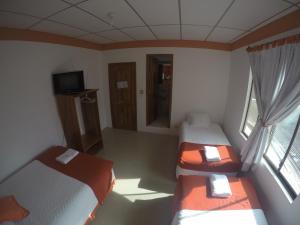 a small room with two beds and a television at Hospedaje SEA LIONS in Puerto Villamil