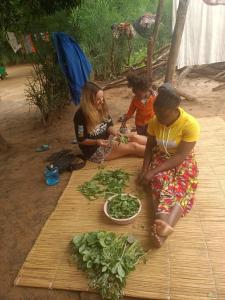 a group of people sitting on a cutting board with vegetables at Muke Village Guest House in Livingstone