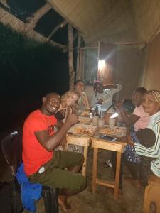 um grupo de pessoas sentadas à volta de uma mesa a comer em Muke Village Guest House em Livingstone