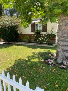 una cerca blanca frente a una casa con un árbol en Orchard house en Los Ángeles