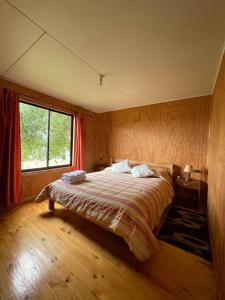 une chambre avec un lit et une fenêtre dans l'établissement Hermosa cabaña a pasos de la playa, à Castro