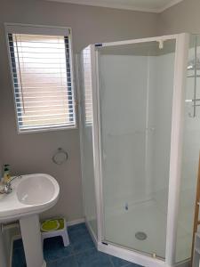 a white bathroom with a shower and a sink at Charming on Charles in Cooks Beach
