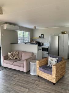 a living room with two couches and a kitchen at Charming on Charles in Cooks Beach