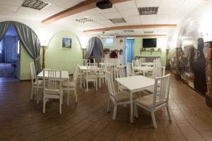 un comedor con mesas y sillas blancas en Postoyaliy Dvor Hotel, en Kirov