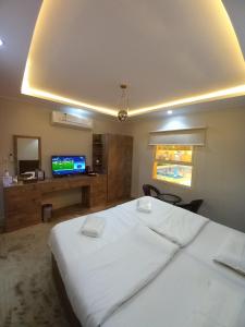 um quarto com uma grande cama branca e uma televisão em دايموند Diamond em Al-ʿUla