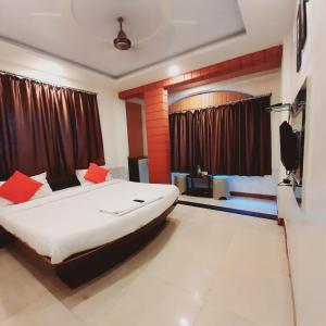a bedroom with a large bed with red pillows at Hotel Savairah Palace in Mahabaleshwar