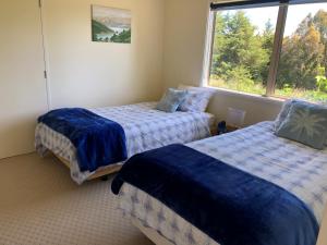 Duas camas num quarto com uma janela em Jennifer's Cottage 
