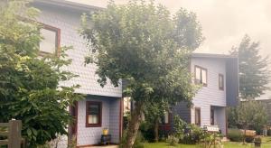 une maison blanche avec un arbre en face dans l'établissement Aysén Cabañas, à Puerto Aisén