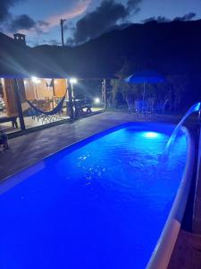 a swimming pool at night with a table and umbrella at Toca - Bairro Serrano in São Bento do Sapucaí