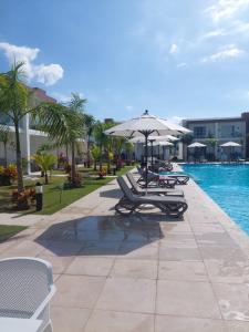 een groep ligstoelen en een parasol naast een zwembad bij Escapada en Boca chica in Boca Chica