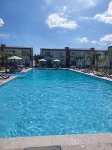 a large blue swimming pool with chairs and umbrellas at Escapada en Boca chica in Boca Chica