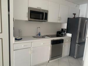 een keuken met witte kasten en een roestvrijstalen koelkast bij Ocean view getaway in Cupecoy