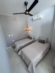 two beds in a bedroom with a ceiling fan at DELAMAR Casa de playa in Coveñas