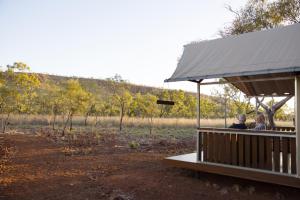 duas pessoas sentadas num convés a olhar para um campo em Bell Gorge Wilderness Lodge em King Leopold Ranges