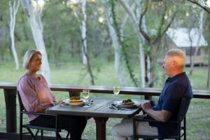a man and a woman sitting at a table at Bell Gorge Wilderness Lodge in King Leopold Ranges