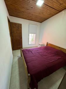 een bed in een kamer met een houten plafond bij Casa dos habitaciones, zona parque in Necochea