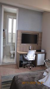 a bedroom with a desk with a television and a chair at Casa das Luzes Hostel IVN in Rio de Janeiro