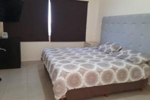 a bedroom with a bed with a gray and white comforter at Casa cerca de parque industrial in Monclova