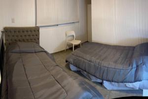 a room with two beds and a chair in it at Depto funcional en Comodoro! in Comodoro Rivadavia +3 photos