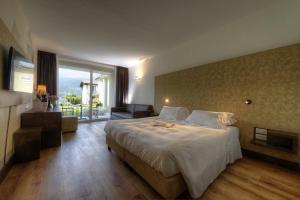 a hotel room with a large bed and a balcony at Bella Hotel & Restaurant with private dock for mooring boats in San Felice del Benaco