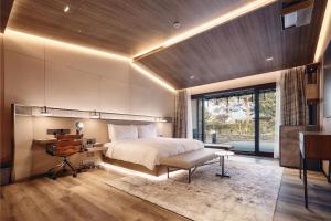 sypialnia z dużym łóżkiem, biurkiem i biurkiem w obiekcie Amber Pure Hill Hotels & Resorts Jeju w mieście Czedżu