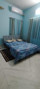 Bett in einem Zimmer mit blauen Wänden und Vorhängen in der Unterkunft Luxurious & Spacious 4BHK Villa with AC at City Centre, Pearl Stayz in Mysore