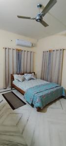 Schlafzimmer mit einem Bett und einem Deckenventilator in der Unterkunft Luxurious & Spacious 4BHK Villa with AC at City Centre, Pearl Stayz in Mysore