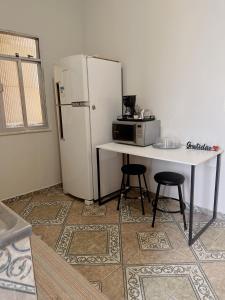 uma cozinha com um frigorífico branco e uma mesa com 2 bancos em Casa alto Vidigal no Rio de Janeiro