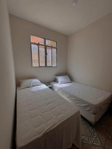 two beds in a small room with a window at Casa alto Vidigal in Rio de Janeiro