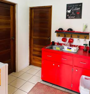 a red kitchen with a red counter and a sink at City Garden Apartment in Belize City