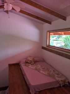 a small bed in a room with a window at Playa Bluff Lodge in Bocas del Toro
