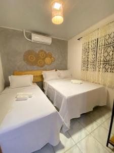 due letti in una stanza con lenzuola bianche di Casa da Praia Japaratinga a Japaratinga Altre 3 foto
